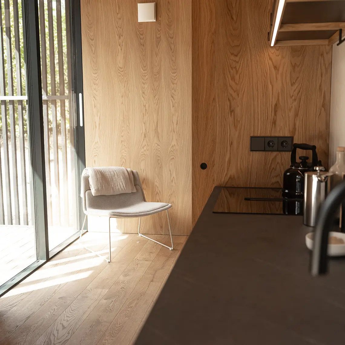 Lounge chair and kitchen corner by the window in a KONGA cabin at Eco by Nature
