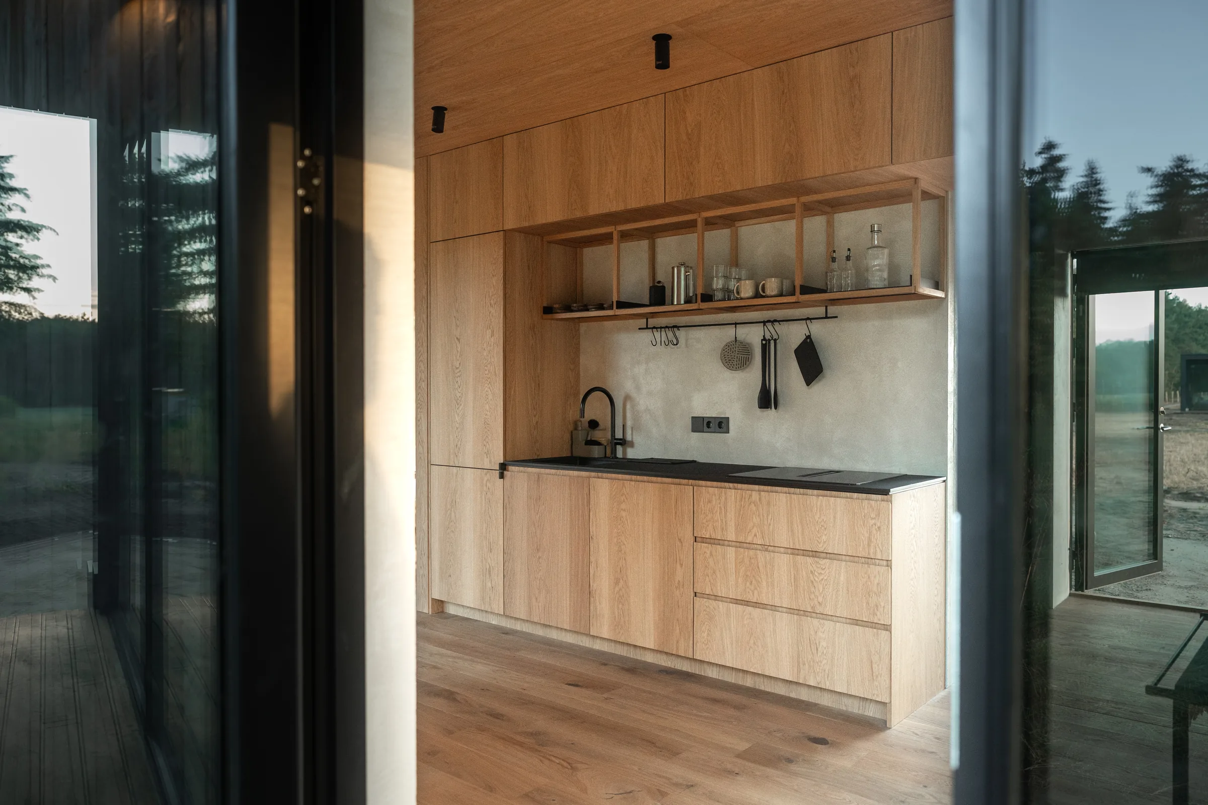 Oak kitchen seen through the glass doors of a KONGA cabin at Eco by Nature