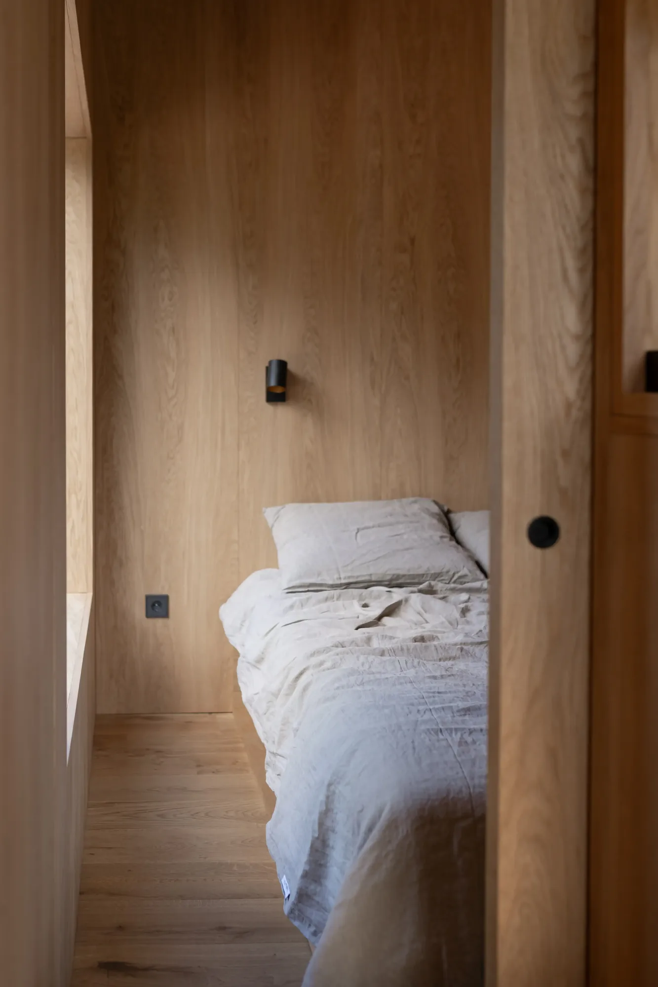 Bedroom with oak-panelled walls in a KONGA cabin at Eco by Nature